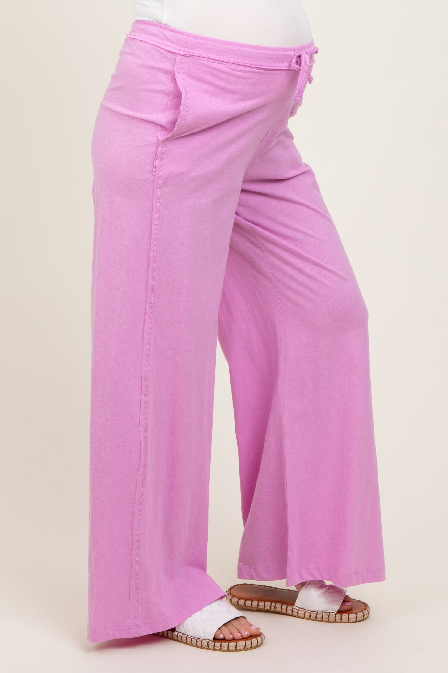 woman wearing light pink maternity wide-leg pants with an elastic waistband and pockets, showing a baby bump