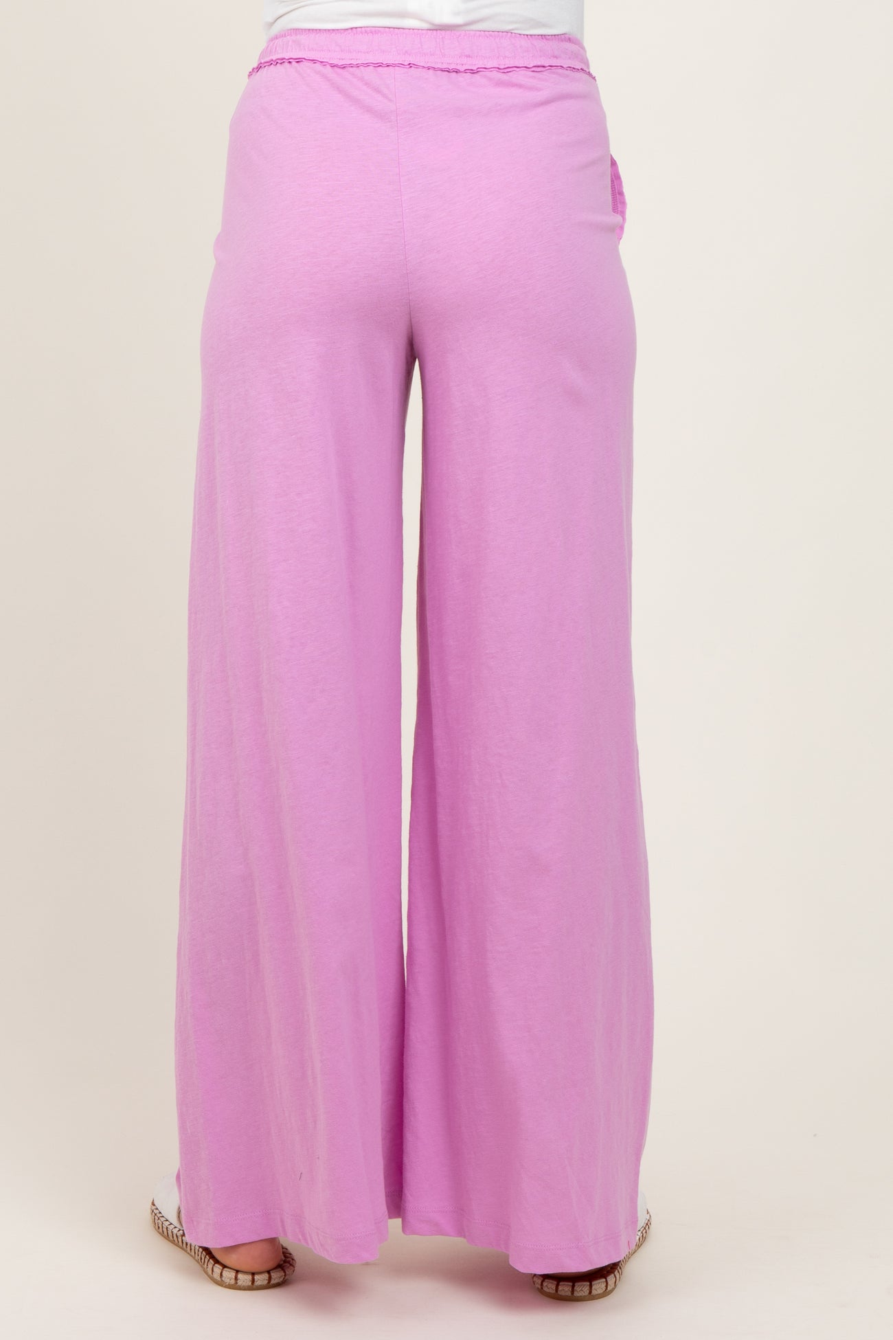 woman wearing pink wide-leg maternity pants, showing the back view of the garment