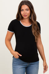 woman wearing a black maternity top with short sleeves and light blue trim, posing with a hand in her pocket