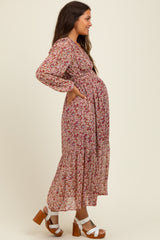 woman wearing a floral maternity dress with long sleeves and a ruffled hem, showcasing her baby bump, paired with brown heels