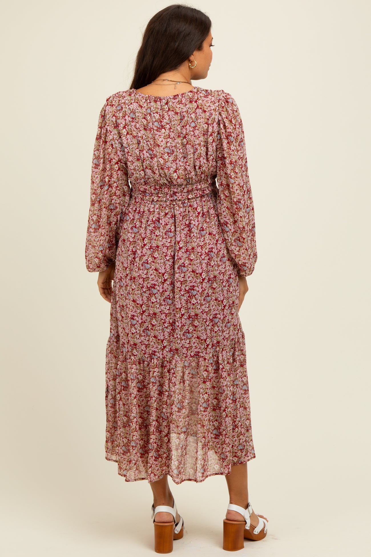woman wearing a floral print maternity dress with long sleeves and a tiered skirt, showing a baby bump