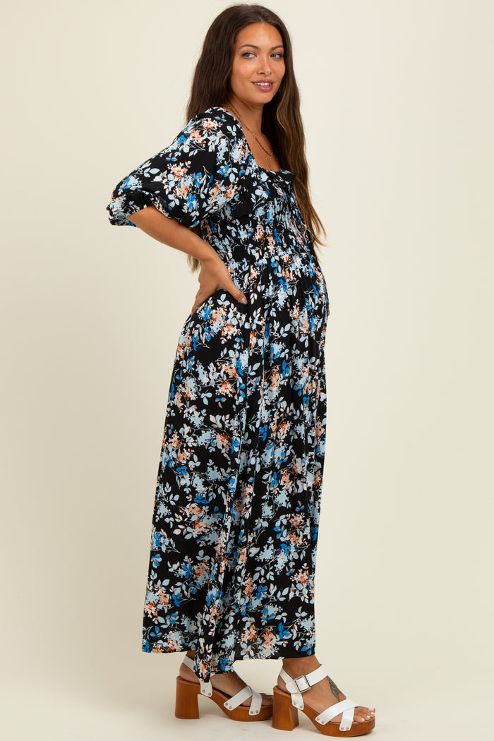 woman wearing a black floral maternity maxi dress with short sleeves and a visible baby bump