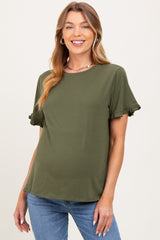 woman wearing an olive green short sleeve maternity top with ruffle details and a visible baby bump