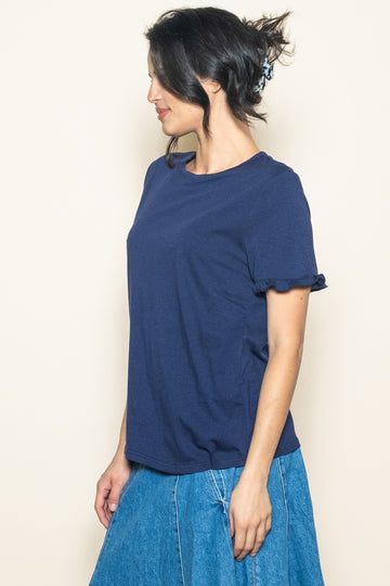 woman wearing a navy blue short sleeve top with ruffled sleeves and a denim skirt