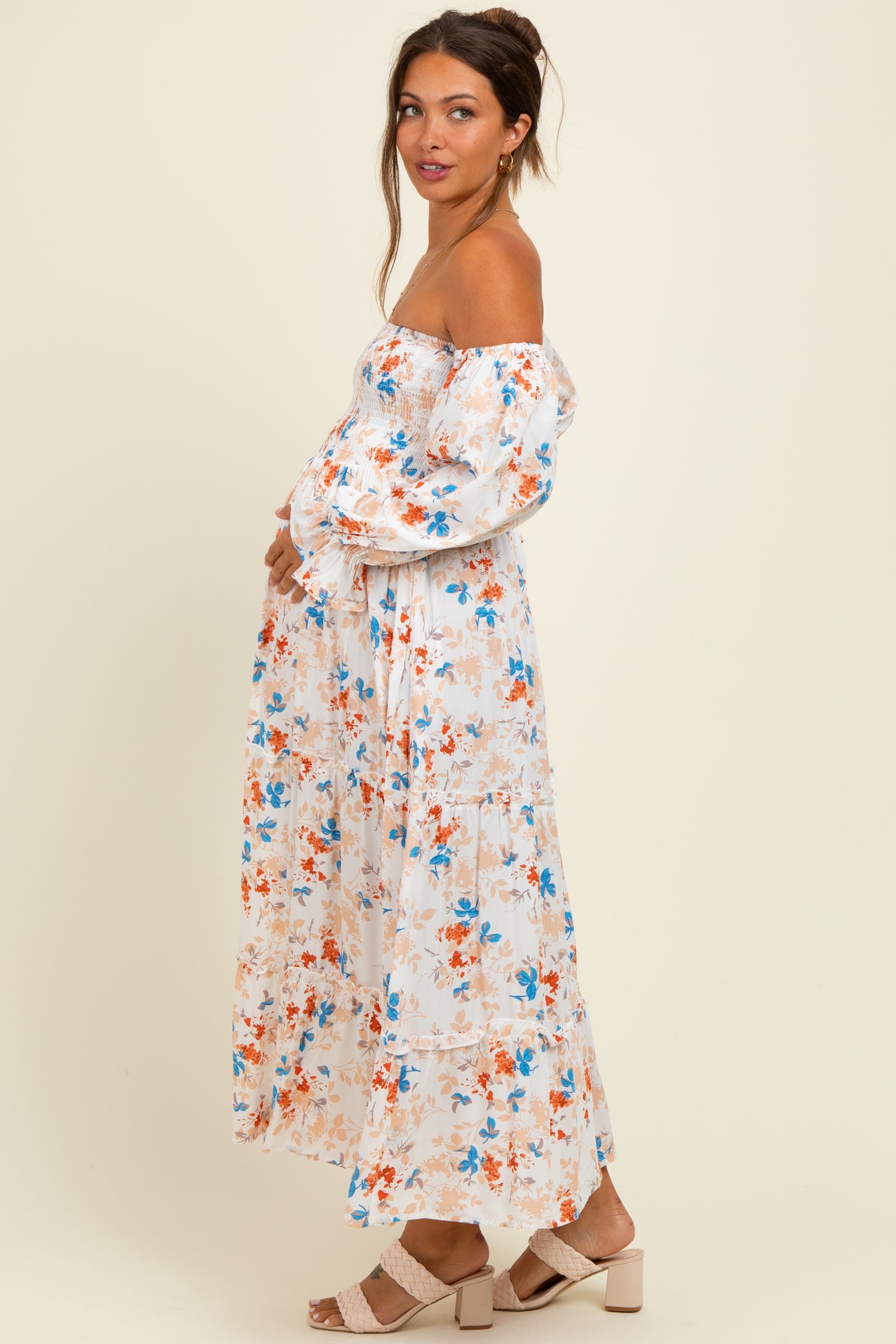 woman wearing a floral off-the-shoulder maternity dress with puff sleeves and a visible baby bump