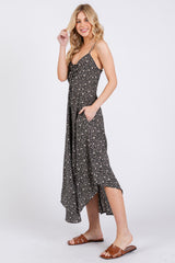 woman wearing a black floral sundress with adjustable straps and pockets, standing in a relaxed pose