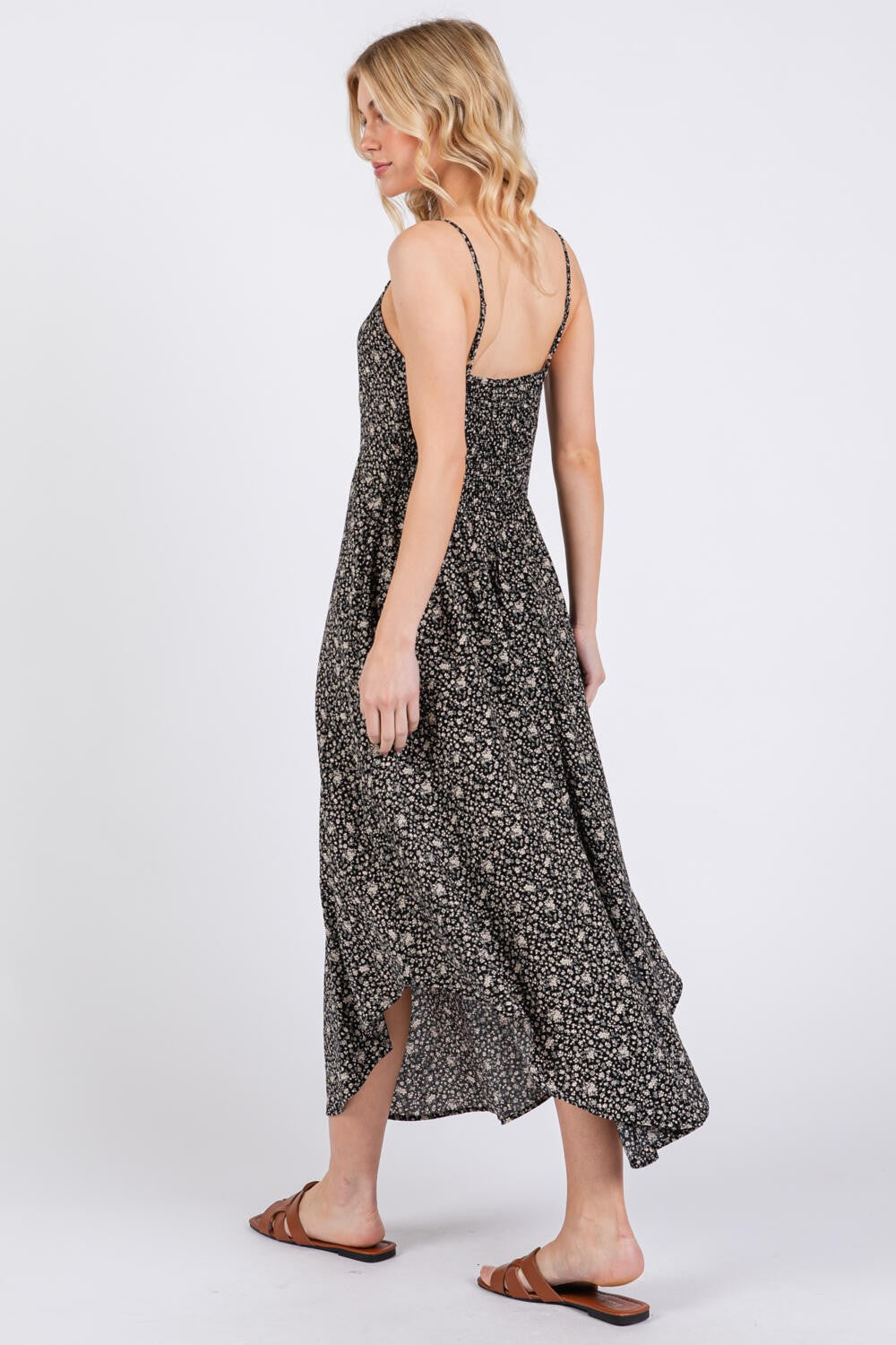 woman wearing a black floral maxi dress with spaghetti straps, seen from the back, styled with brown sandals