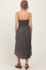 woman wearing a black floral maternity dress with adjustable spaghetti straps and a shirred back, showing a flowing hemline