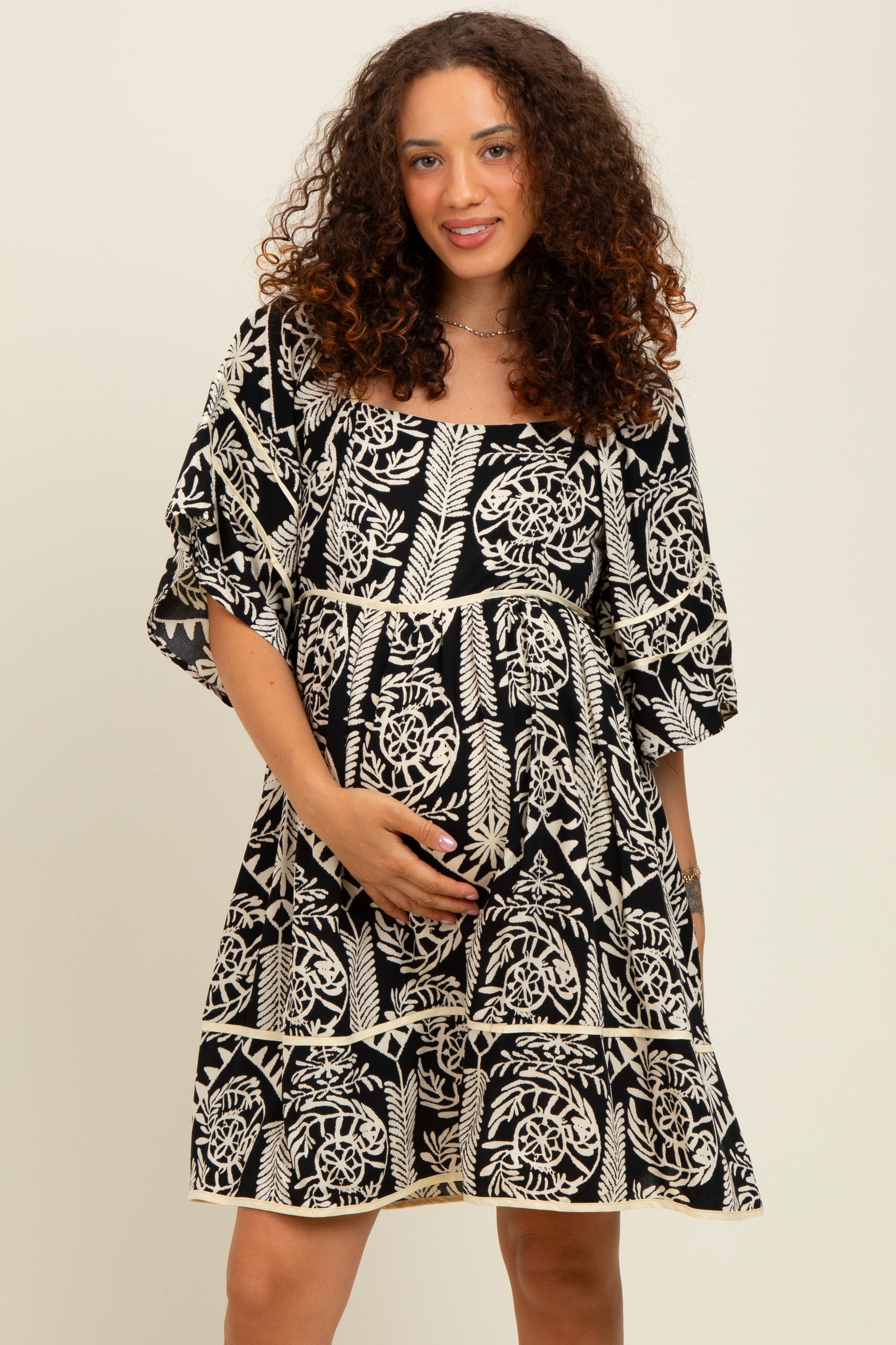 woman wearing a black and white floral maternity dress with short sleeves and a baby bump visible