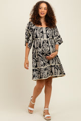 woman wearing a black and white floral print maternity dress, holding her baby bump while walking