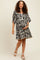 woman wearing a black and white floral print maternity dress, holding her baby bump while walking