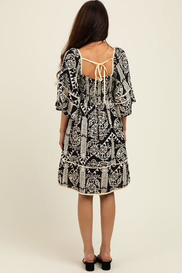 woman wearing a black and white patterned dress with flutter sleeves and back tie detail