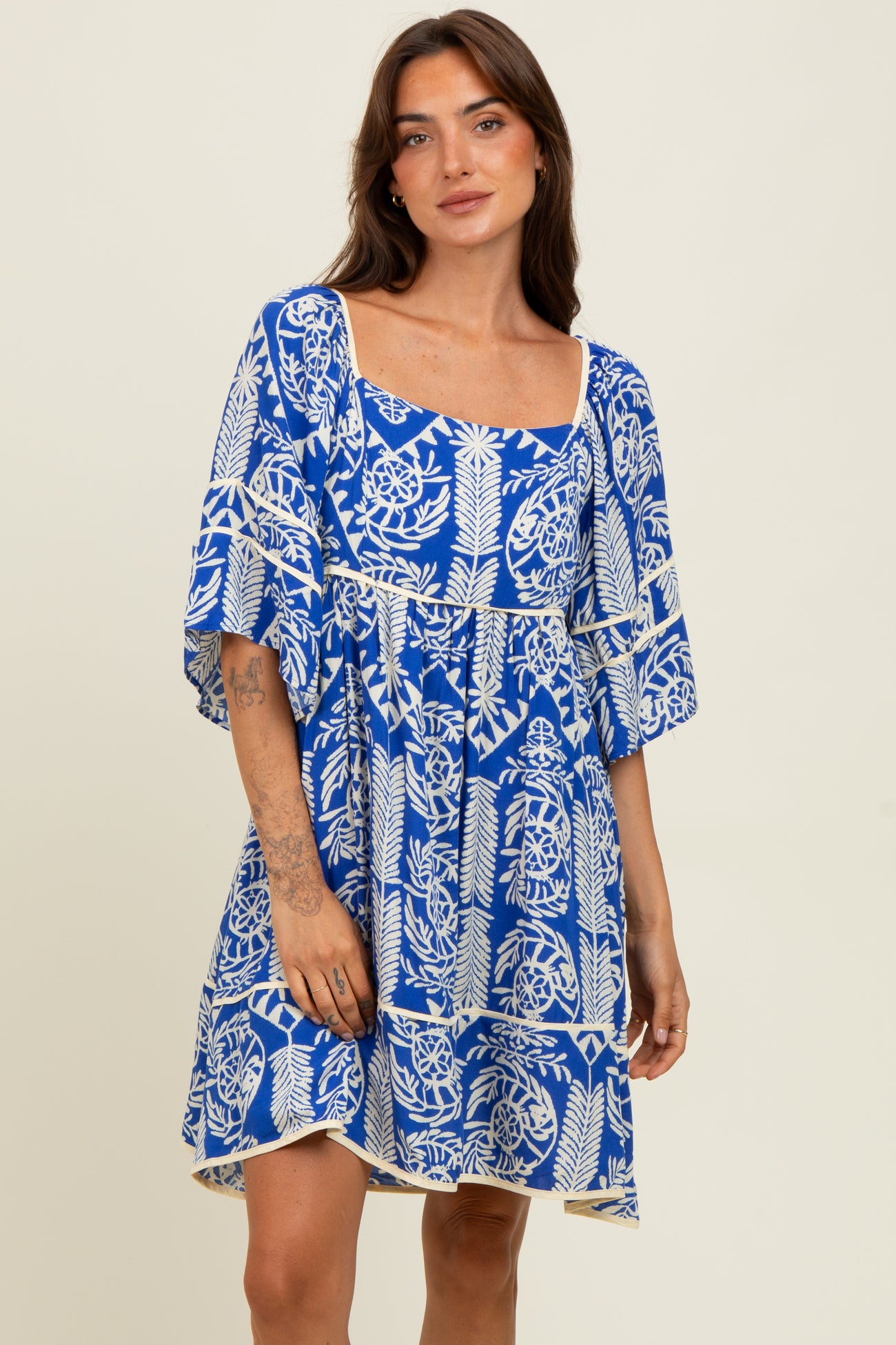 woman wearing a vibrant blue short sleeve dress with a floral print and a square neckline