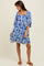 woman wearing a blue and white floral print short dress with puff sleeves and a tiered hemline