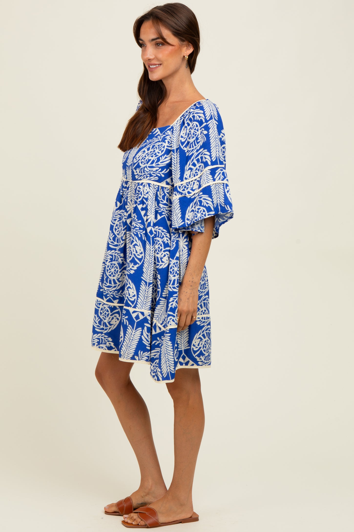 woman wearing a blue and white patterned short sleeve summer dress and brown slide sandals