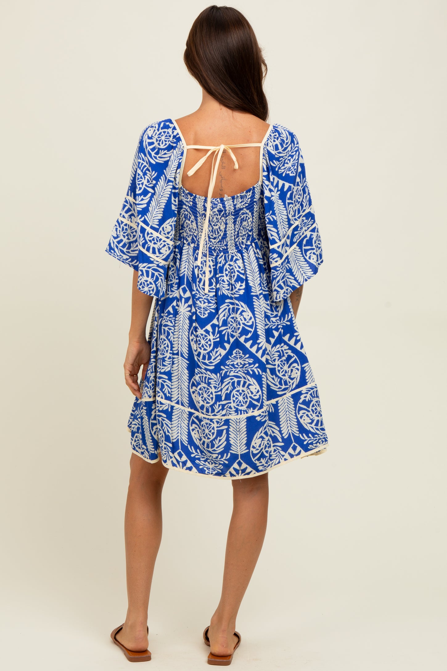woman wearing a blue and white patterned short sleeve dress with a tie back detail and a relaxed fit
