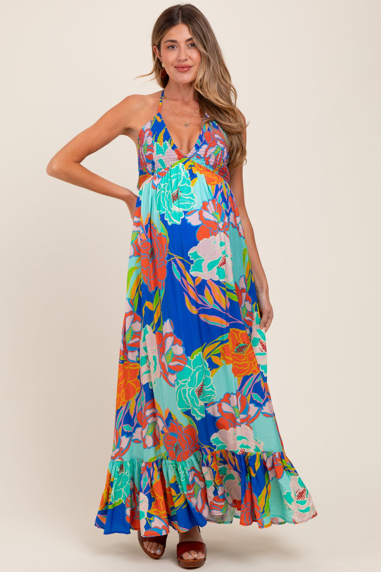 woman wearing a vibrant floral maternity maxi dress with a halter neckline and ruffled hem, showcasing her baby bump