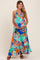 woman wearing a colorful floral maternity maxi dress with a halter neckline, holding her baby bump