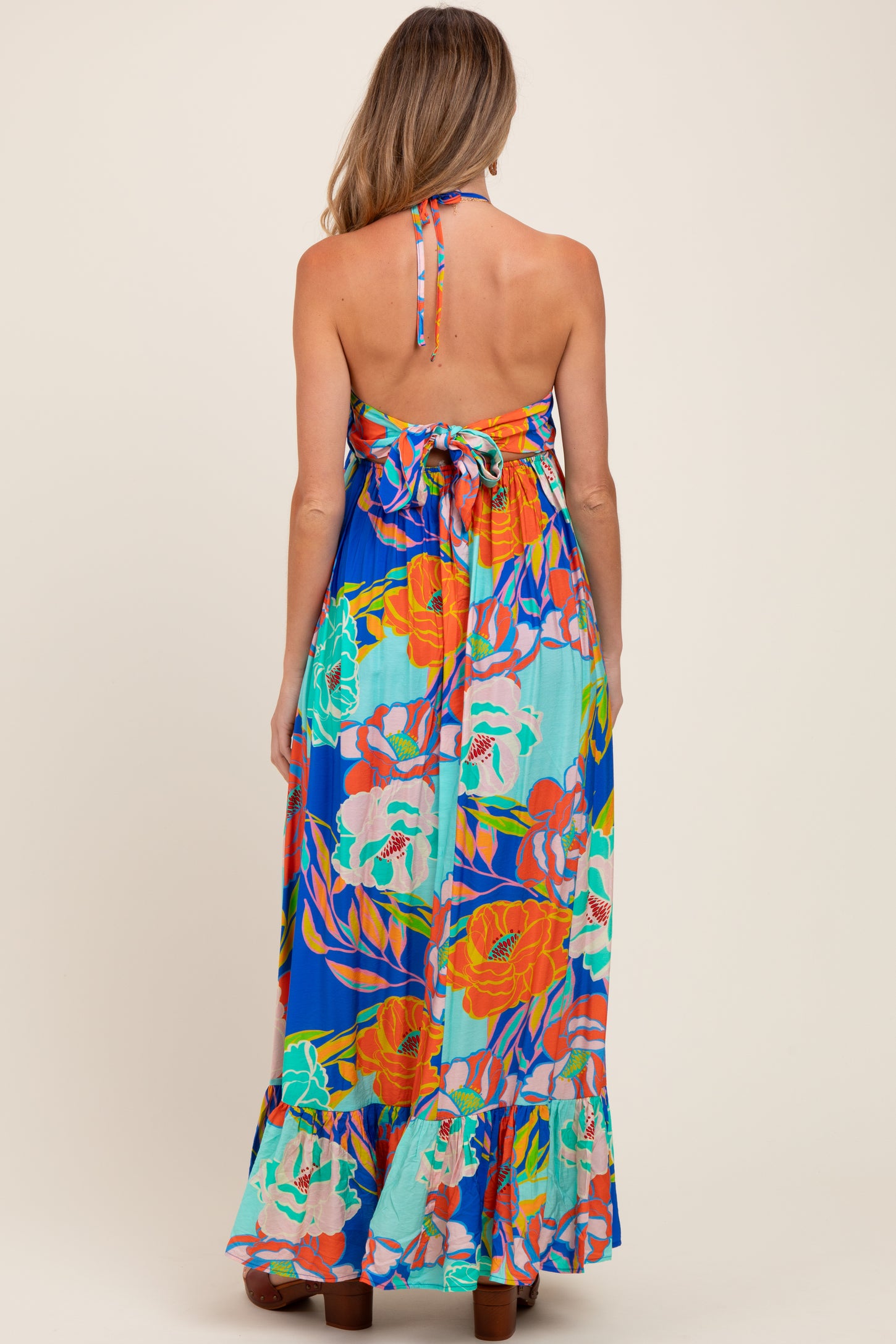 woman wearing a colorful floral maternity maxi dress with a halter neck and open back