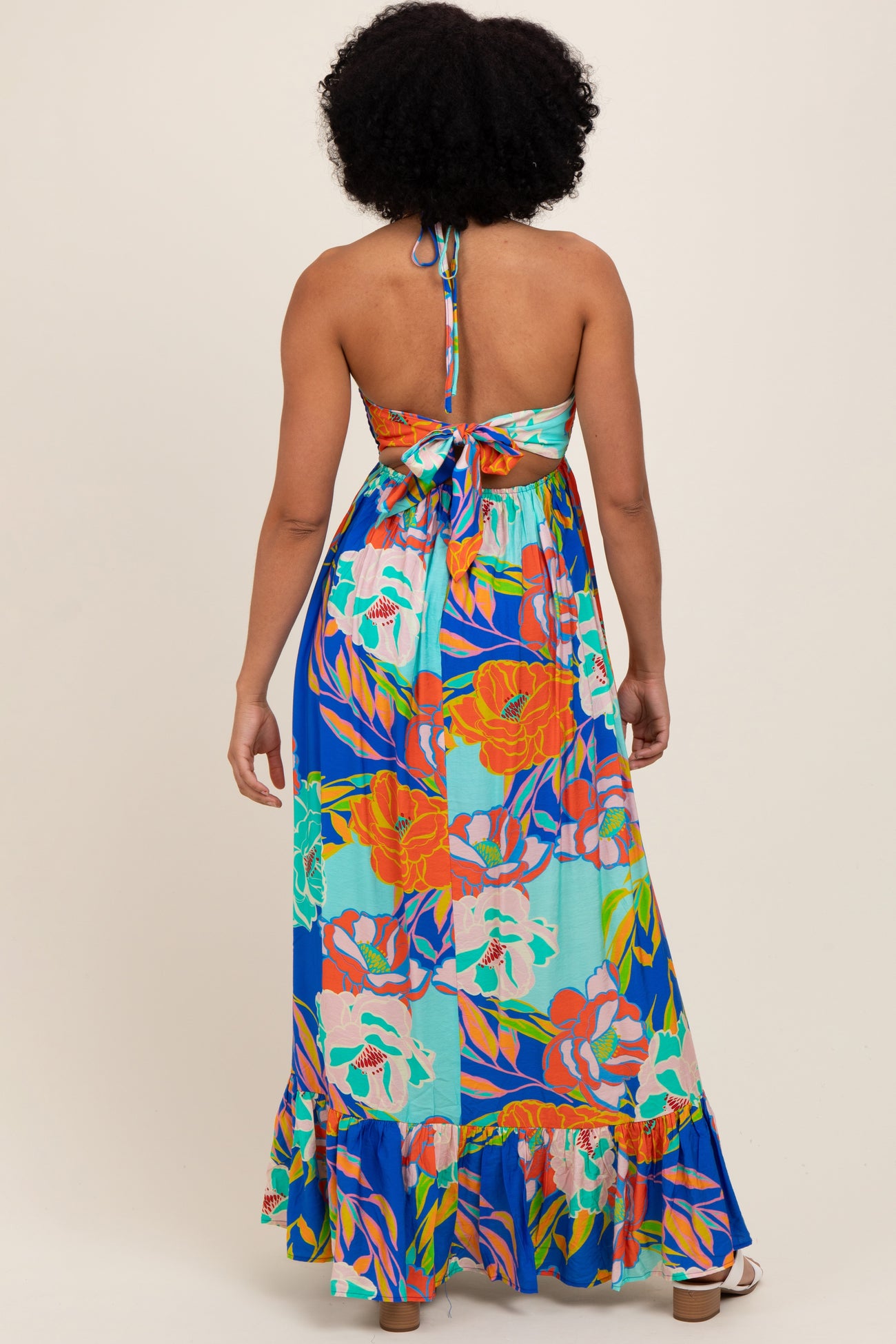 woman wearing a backless floral maxi dress with a halter tie and ruffled hem