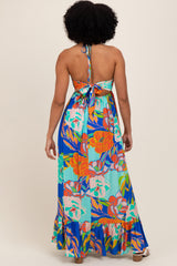 woman wearing a backless floral maxi dress with a halter tie and ruffled hem