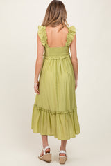 woman wearing a light green maternity dress with ruffled straps and a tiered skirt, showing her back