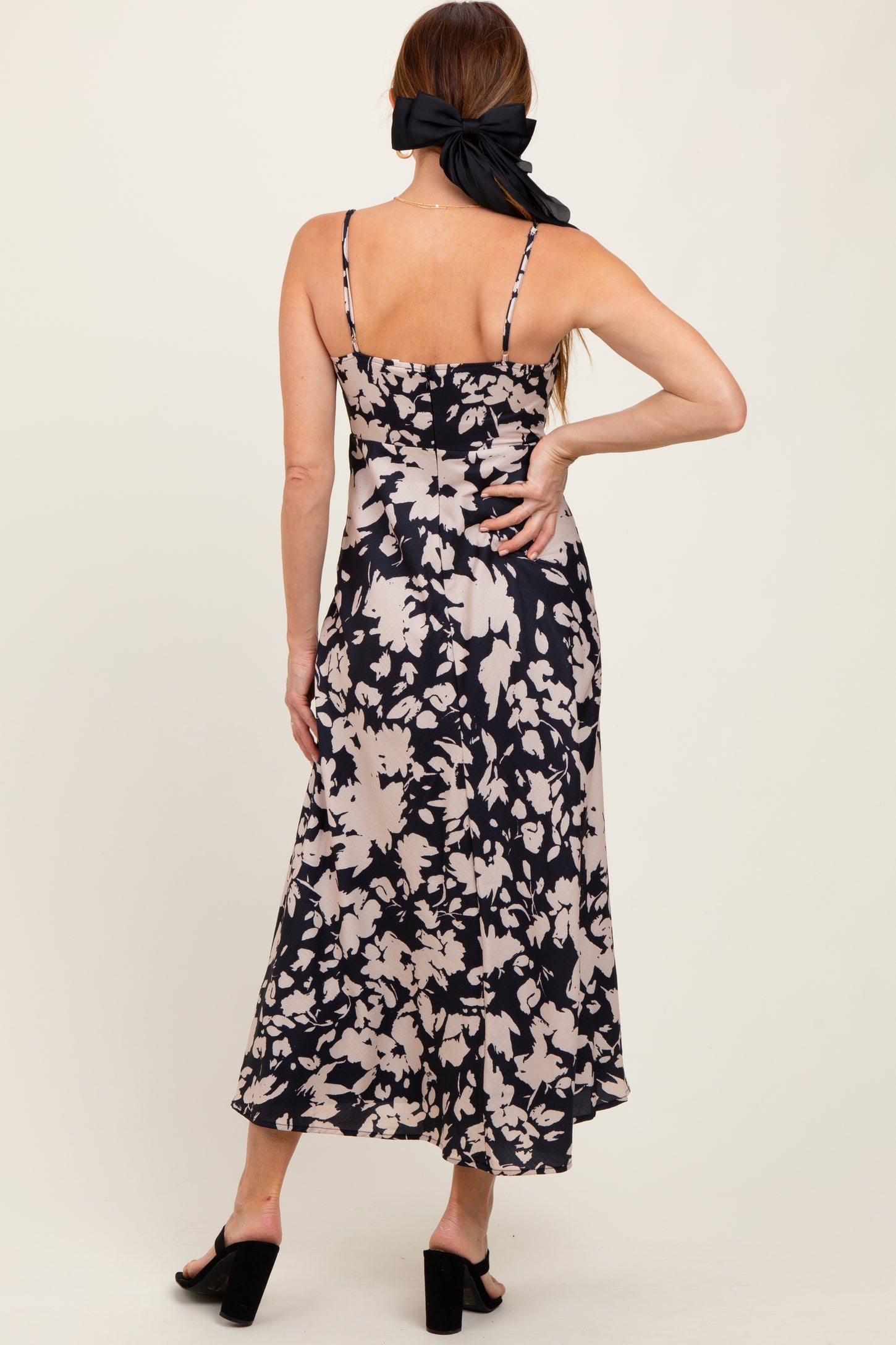 woman wearing a navy blue floral midi dress with thin straps and a flowy silhouette, seen from the back