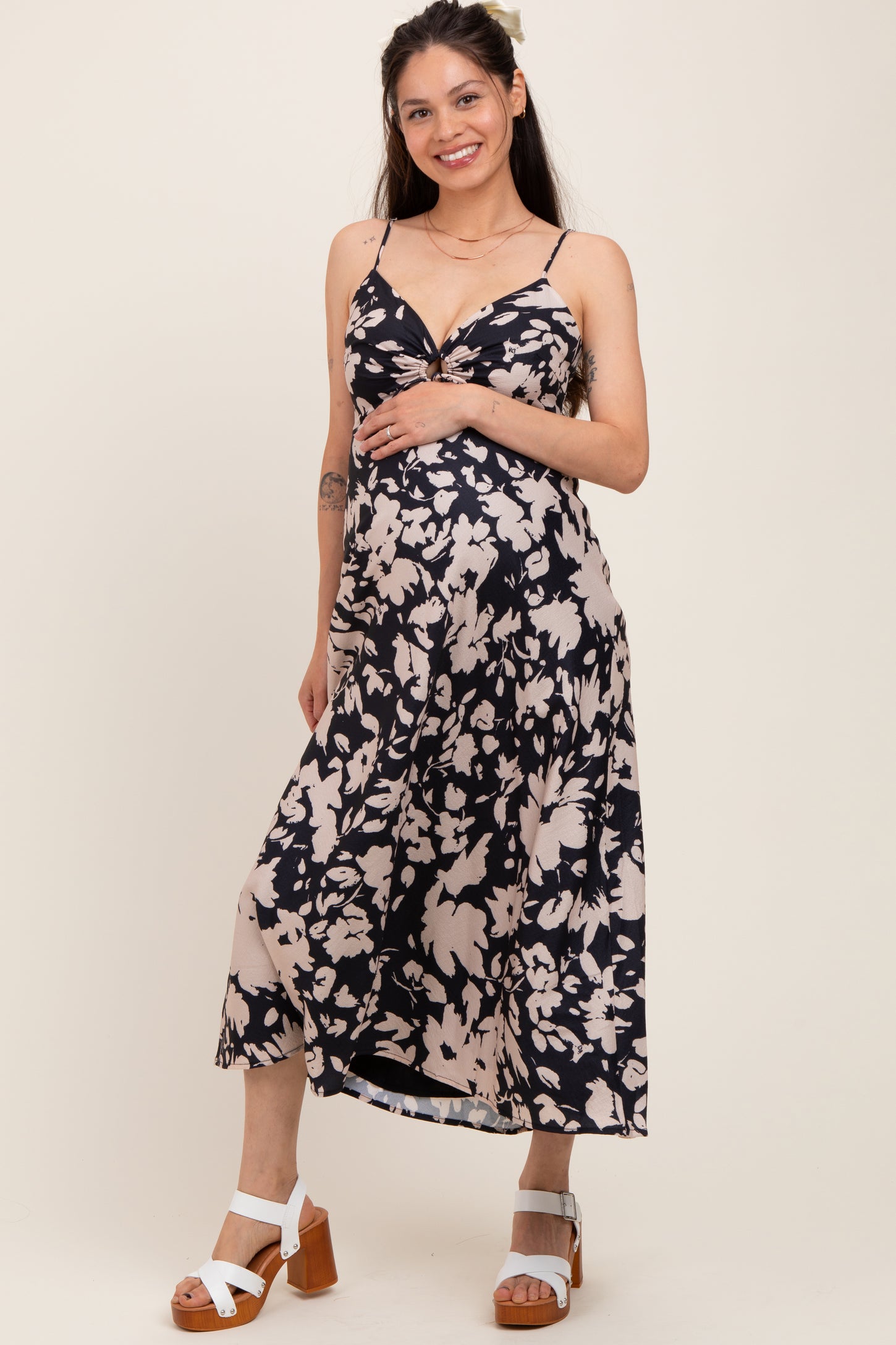 woman wearing a navy and beige floral maternity dress with adjustable straps and a visible baby bump