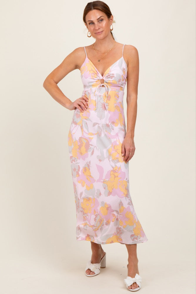 woman wearing a pink and yellow floral slip dress with a front knot detail and spaghetti straps
