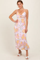 woman wearing a pink and yellow floral slip dress with a front knot detail and spaghetti straps