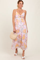 woman wearing a floral spaghetti strap maxi dress in pastel colors and holding a woven handbag