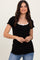 woman wearing a black short sleeve ribbed top with a white bow detail at the neckline and blue jeans