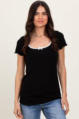 woman wearing a black short sleeve top with a white bow detail at the neckline