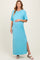 woman wearing a light blue maternity maxi dress with short sleeves and a side slit, gently cradling her baby bump
