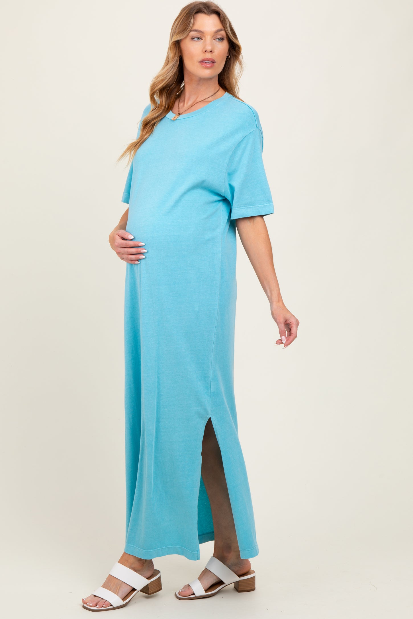 woman wearing a turquoise short sleeve maternity dress with side slits and a visible baby bump