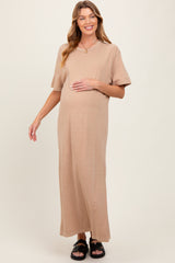 woman wearing a beige short sleeve maxi maternity dress and holding her baby bump
