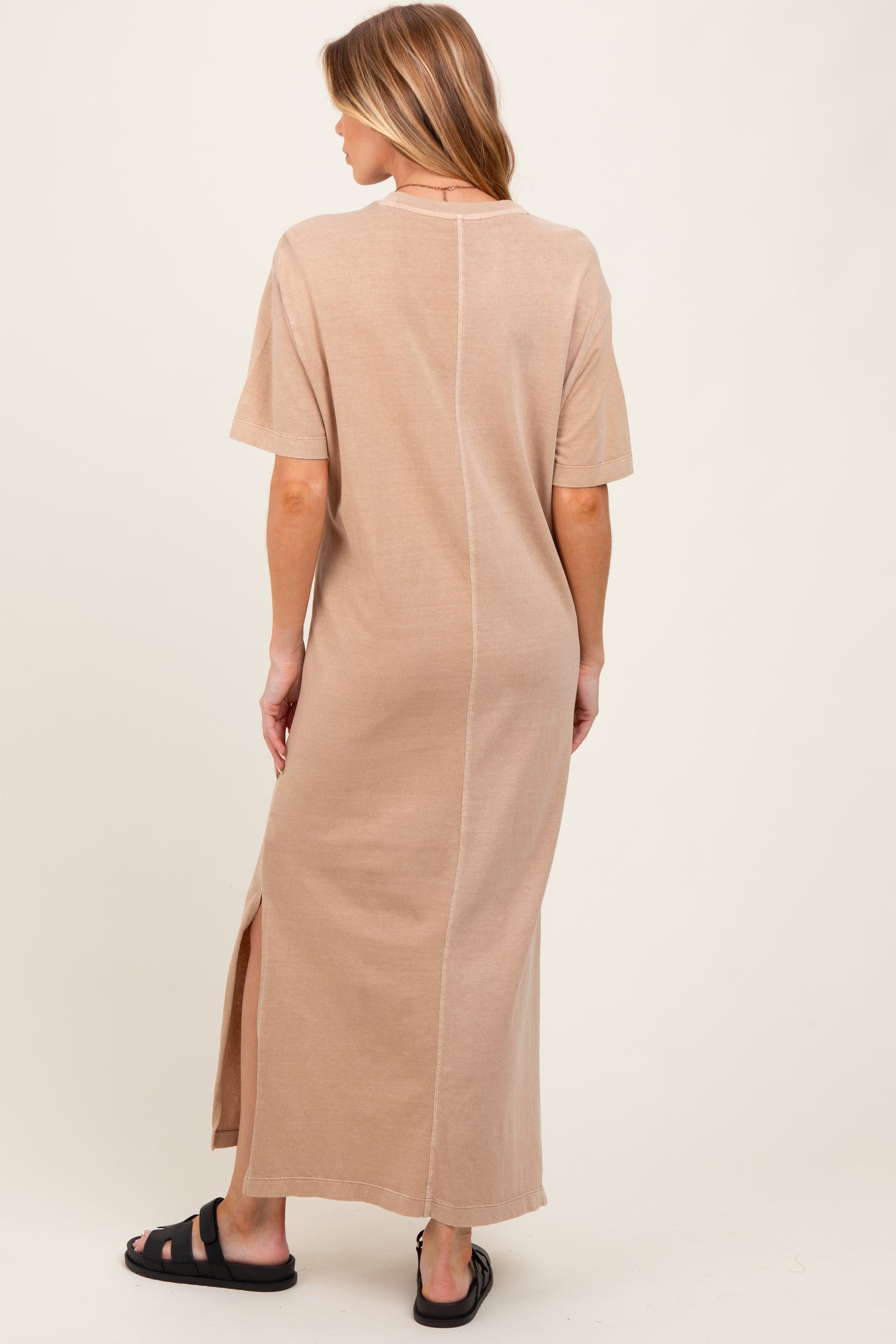 woman wearing a beige maternity maxi dress with short sleeves and a side slit, viewed from the back