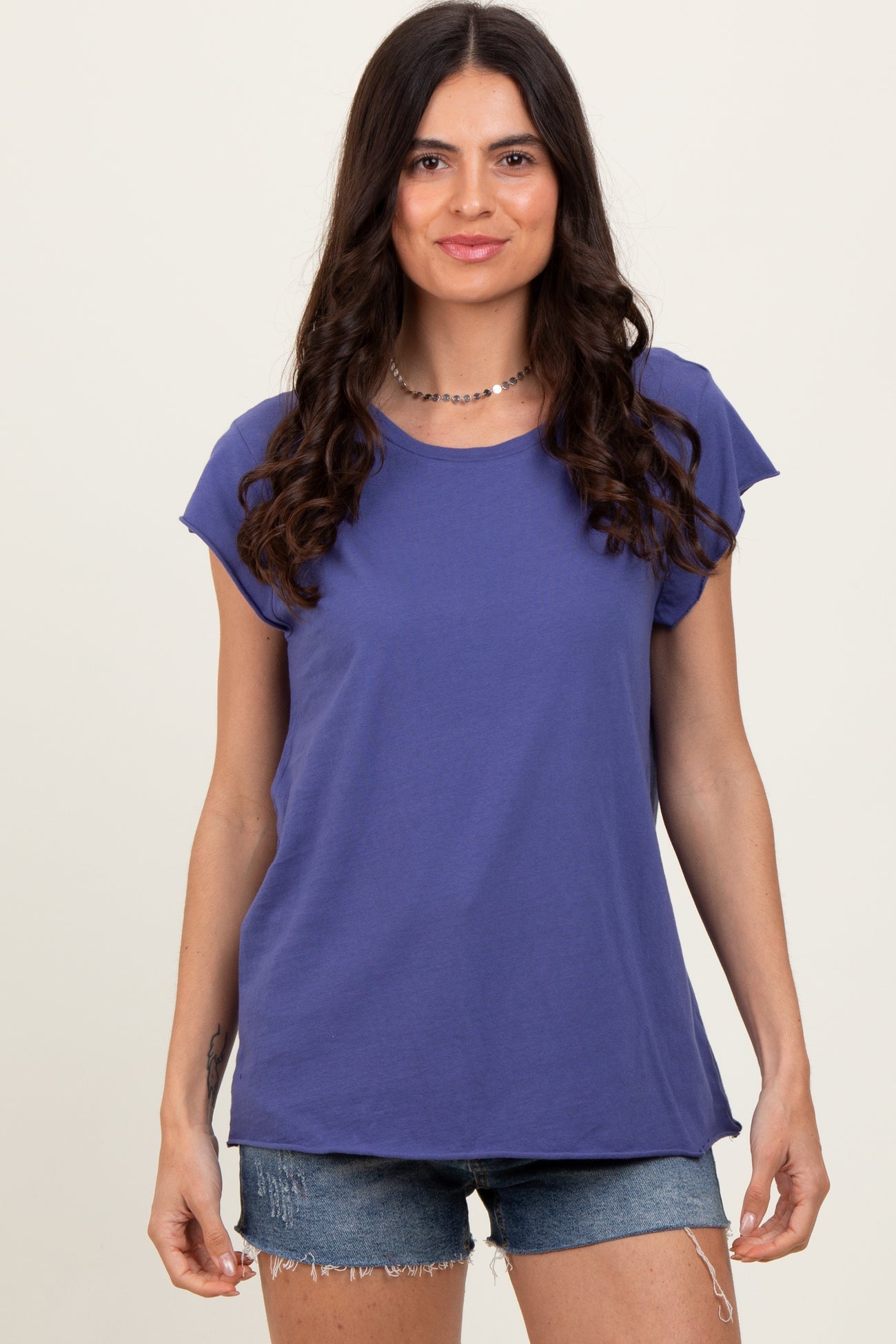 woman wearing a purple short sleeve t-shirt and denim shorts