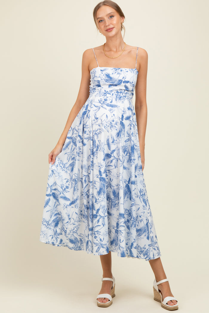 woman wearing a blue floral maternity dress with spaghetti straps and a flowing skirt, showcasing her baby bump