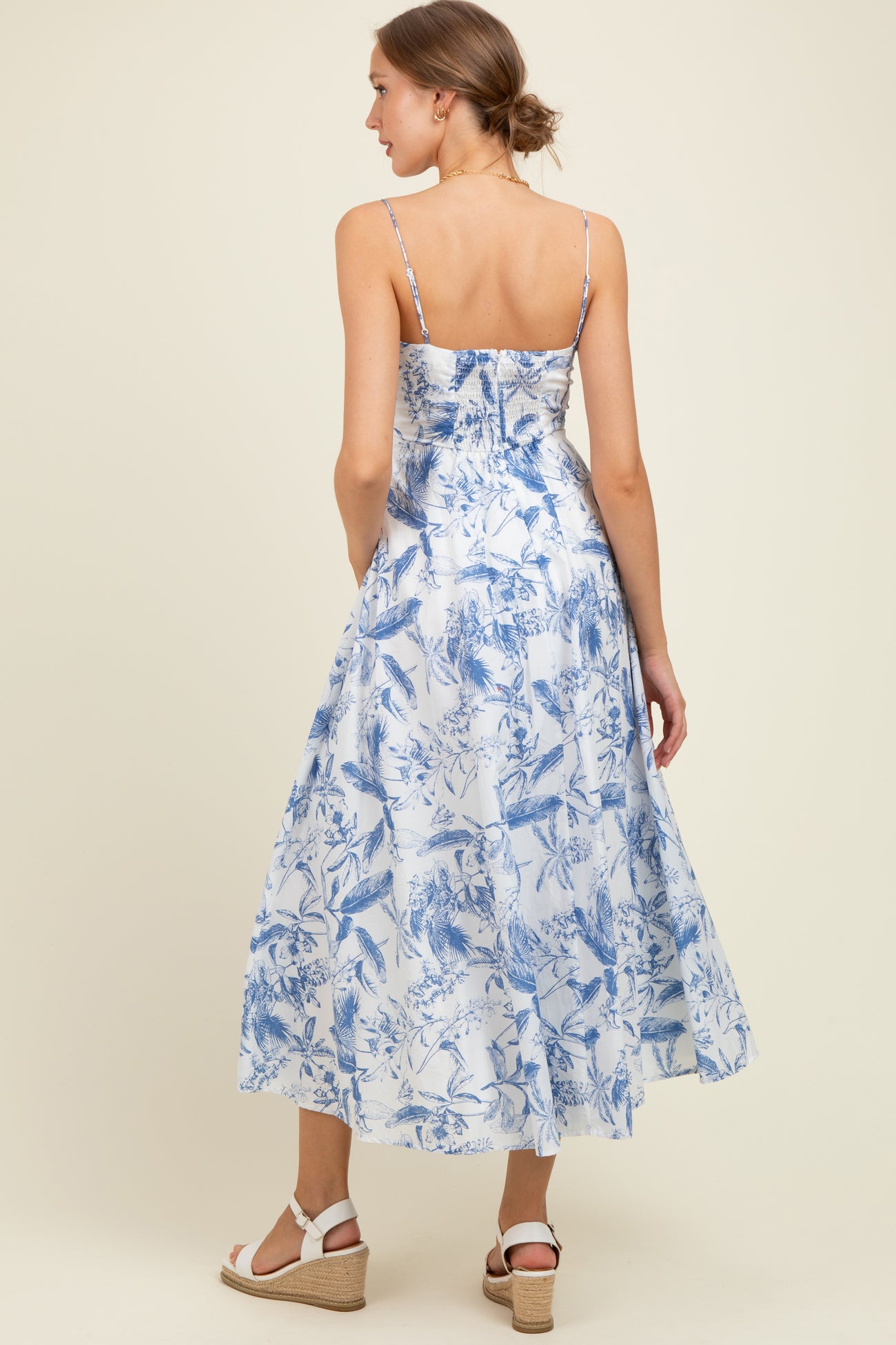woman wearing a blue and white floral maternity maxi dress with adjustable spaghetti straps and a flowing skirt