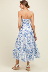 woman wearing a blue and white floral maternity maxi dress with adjustable spaghetti straps and a flowing skirt