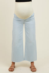 woman wearing light blue wide-leg maternity jeans with a cream-colored belly panel, showing a visible baby bump