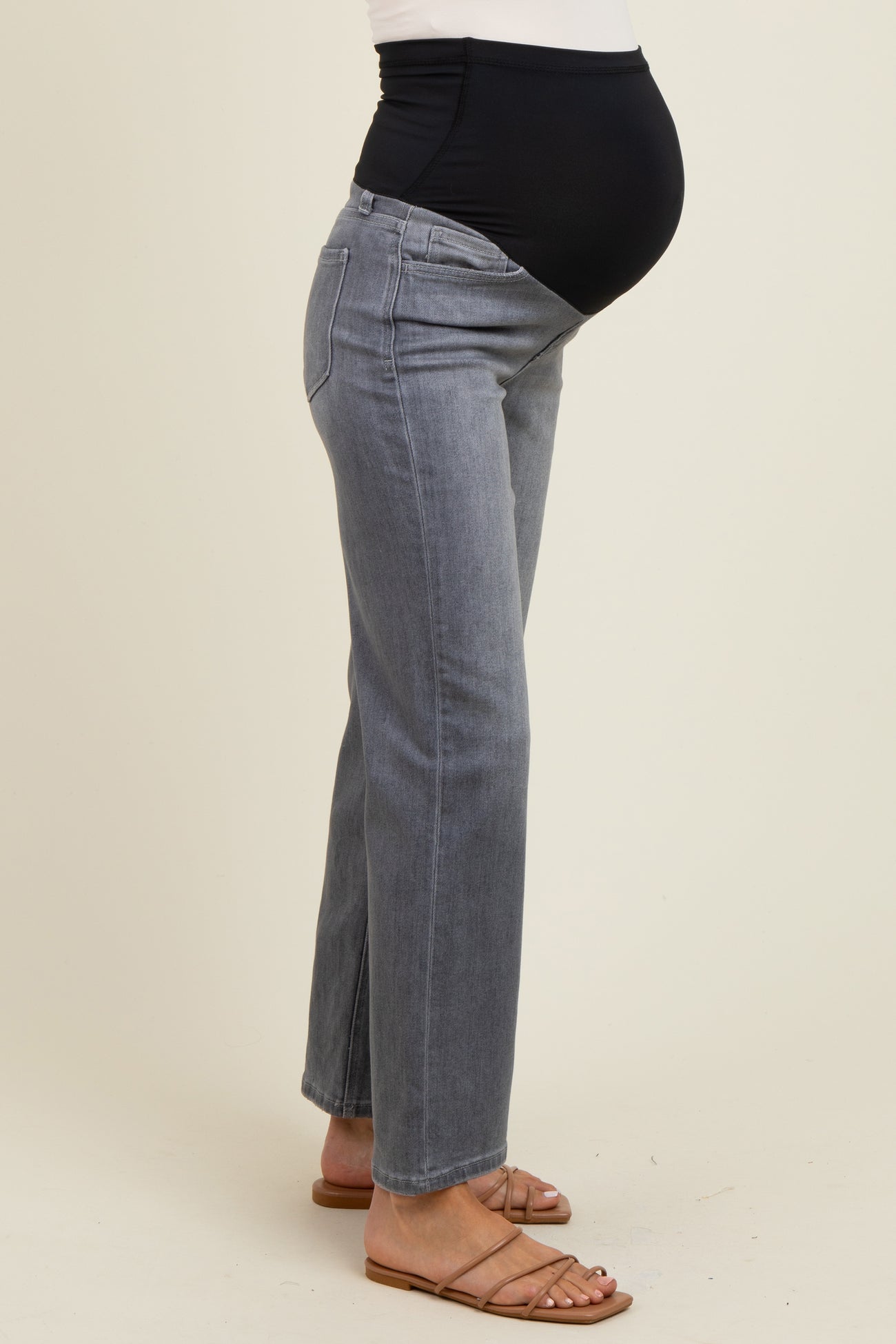 woman wearing gray maternity jeans with a black over-the-bump waistband and visible baby bump