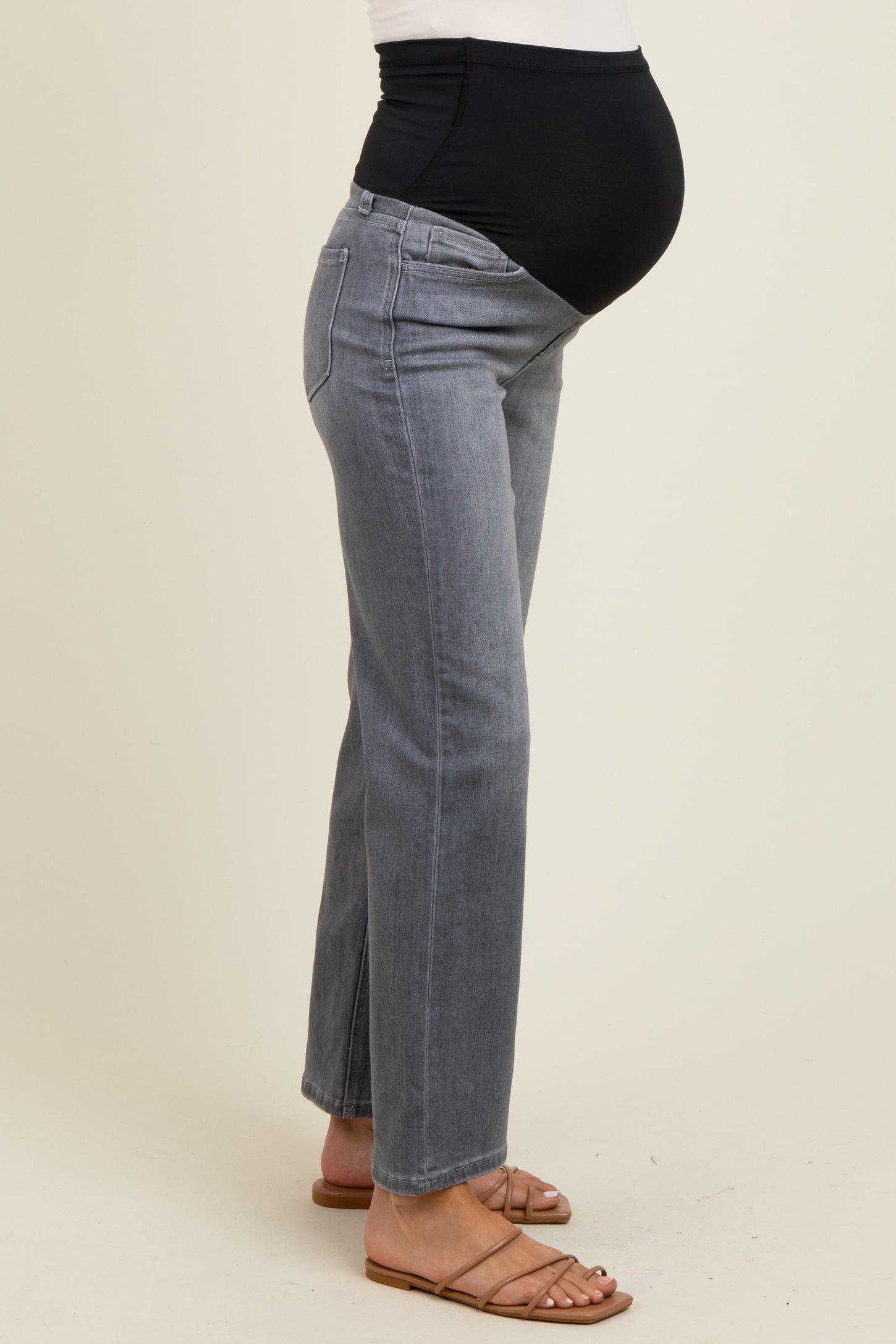 woman wearing gray maternity jeans with a black over-the-bump waistband and visible baby bump
