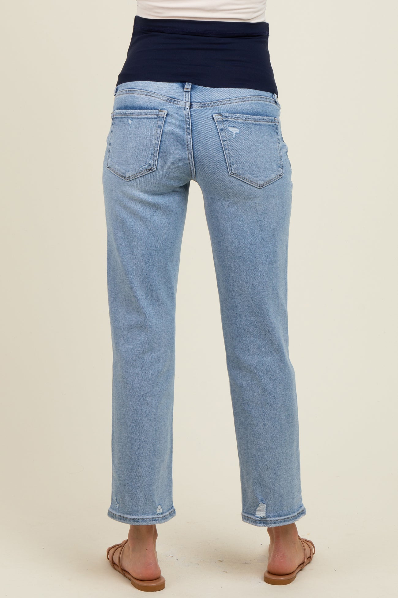 woman wearing light blue maternity jeans with a dark navy waistband and distressed details on the back