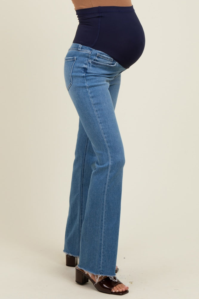 woman wearing a pair of light blue maternity flared jeans with a navy panel and a visible baby bump