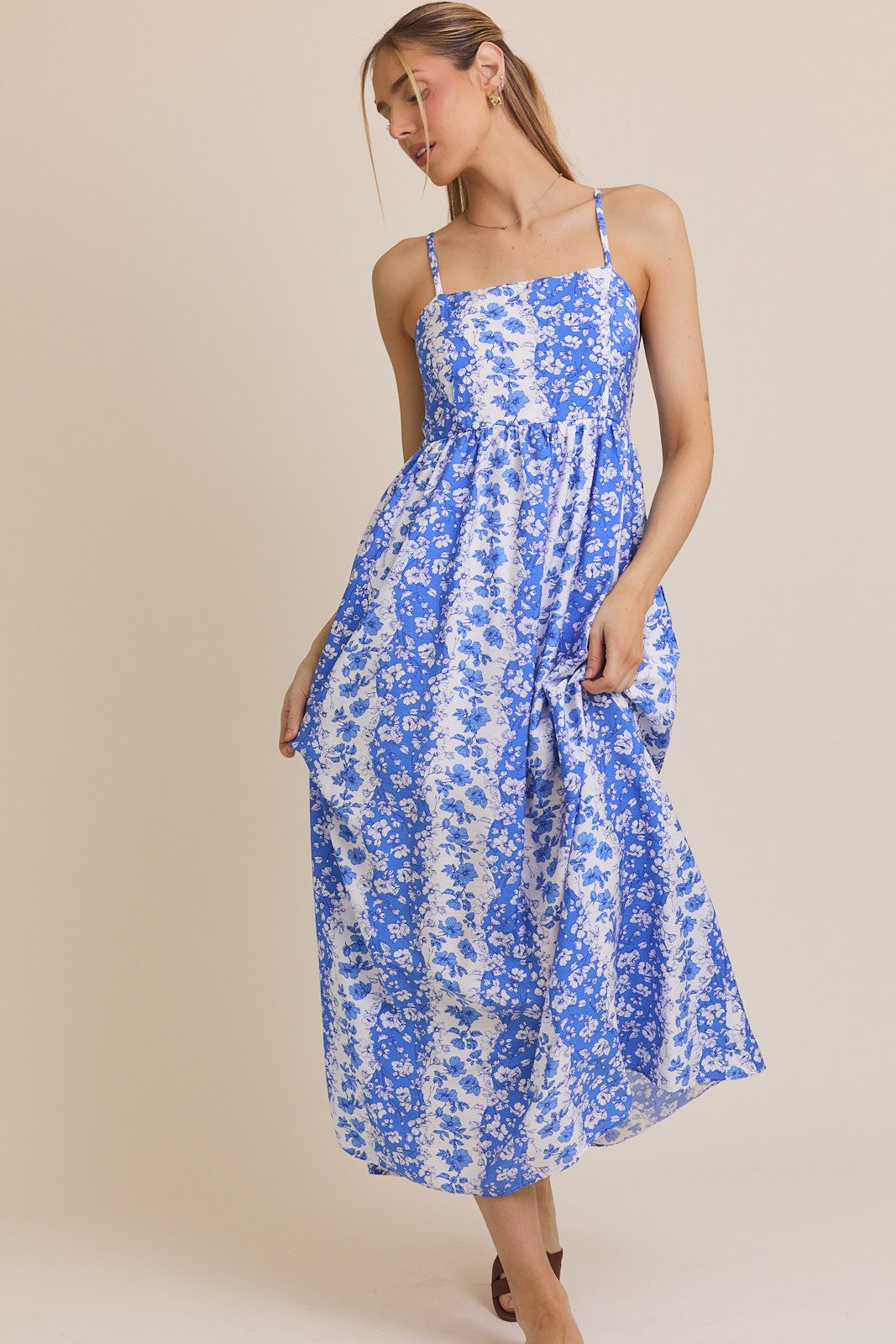 woman wearing a blue and white floral maxi dress with spaghetti straps and a fitted bodice
