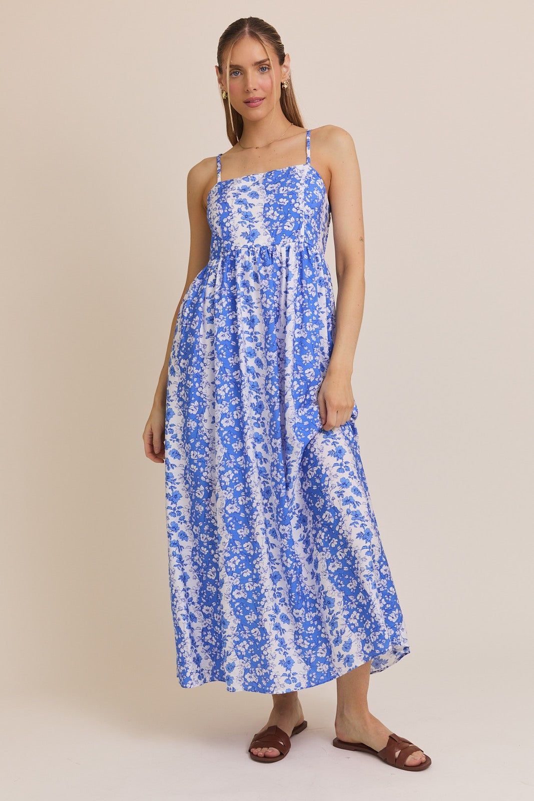 woman wearing a blue and white floral maxi dress with thin straps and a loose fit