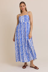 woman wearing a blue and white floral maxi dress with thin straps and a loose fit