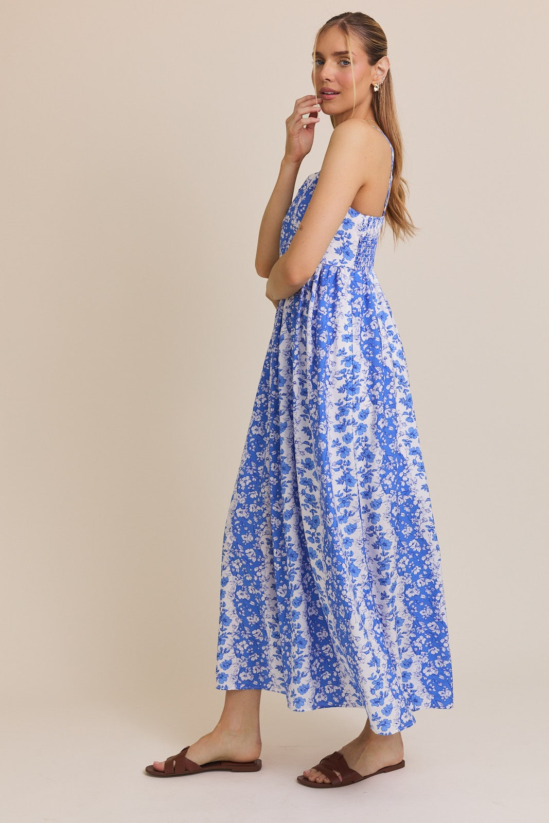 woman wearing a blue and white floral maxi dress with spaghetti straps and a flowy silhouette